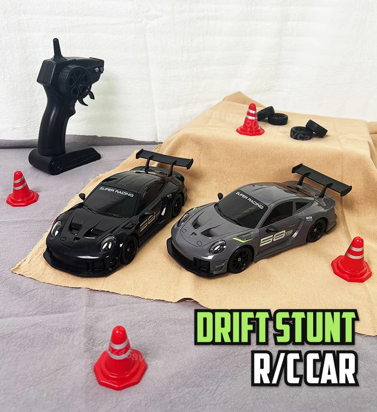 A black and gray RC drift stunt car is displayed on a tan cloth with several red traffic cones.