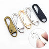 A collection of various metal zipper pulls in gold and black finishes, shown alongside a close-up of a silver pull being held