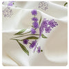 Nahaufnahme eines weißen Baumwollstoffs mit einem lila Lavendelblumenmuster.