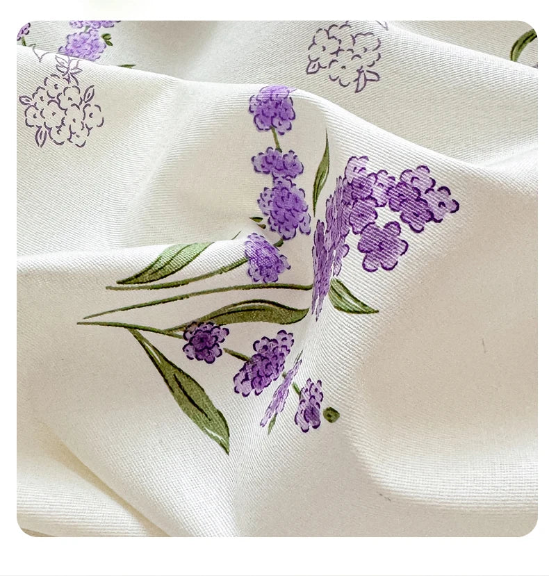 Nahaufnahme eines weißen Baumwollstoffs mit einem lila Lavendelblumenmuster.