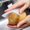 Une main tient une pomme de terre jaune avec un écume silicone et un brosse à fissures attachés.