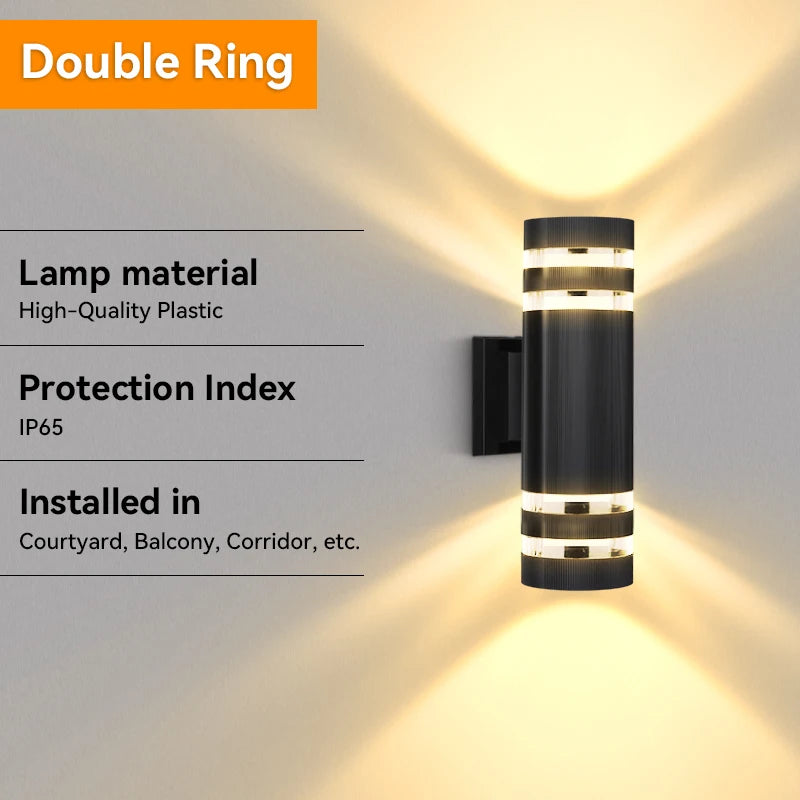 A modern double ring LED wall sconce with a black finish casting a bright light on a white wall.