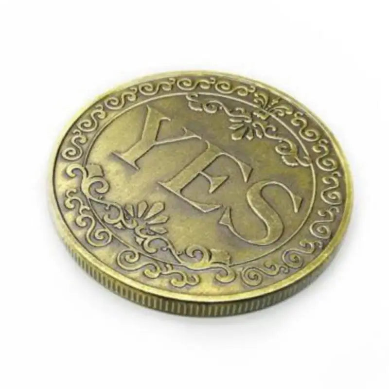 A round, antique gold-toned commemorative coin with the letters YES embossed on the surface.