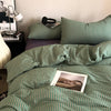 A close-up of a green and white striped duvet cover set with matching pillowcases on a bed.