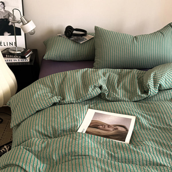 A close-up of a green and white striped duvet cover set with matching pillowcases on a bed.