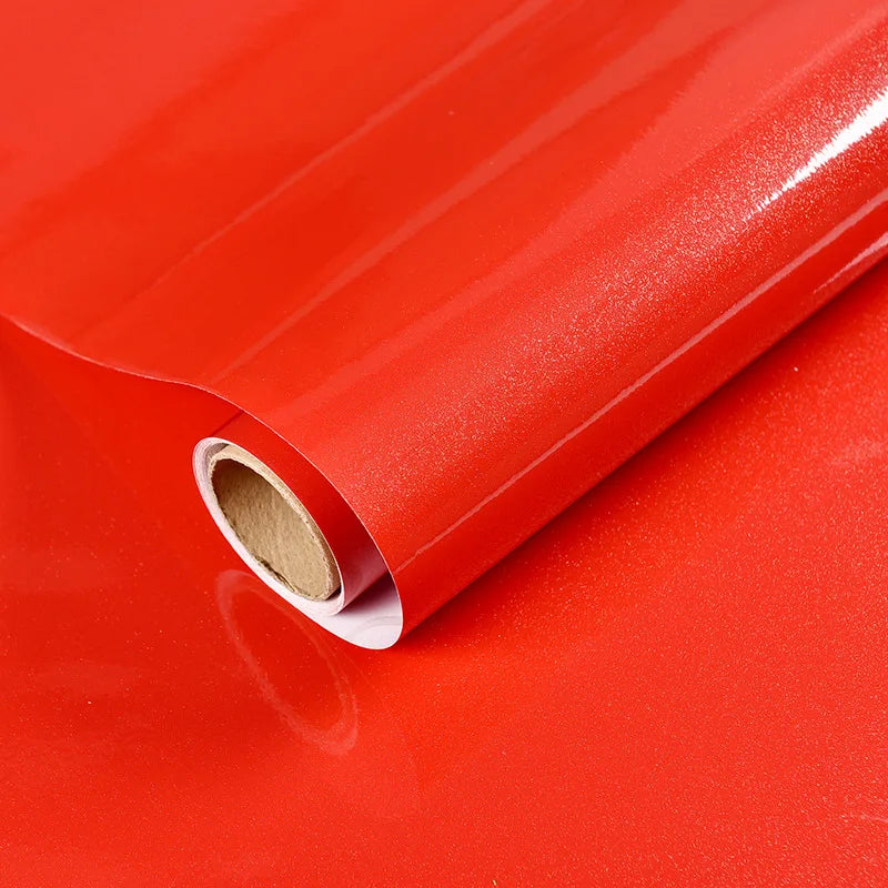 Roll of red marble peel-and-stick kitchen backsplash film shown rolled up on a reflective surface.