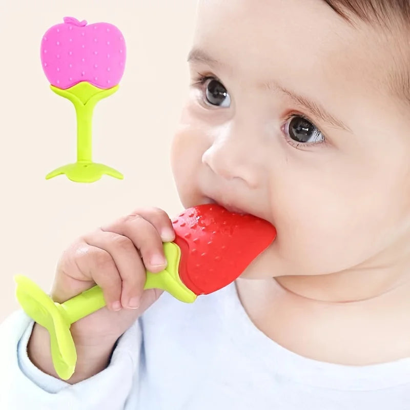 A baby is using a pink silicone strawberry teether to soothe their mouth.