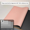 A pink premium PU leather desk mat shown in a folded or rolled state on a dark surface.