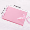 Pink scrapbook album with loose-leaf pages shown on a white wooden surface.