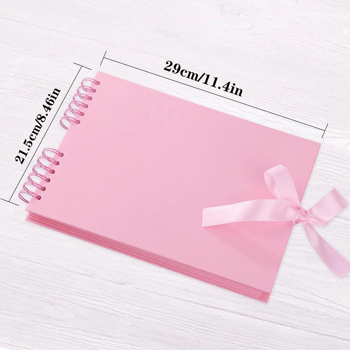 Pink scrapbook album with loose-leaf pages shown on a white wooden surface.