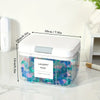 A clear plastic container holding colorful laundry pods with a silver lid on a white surface.