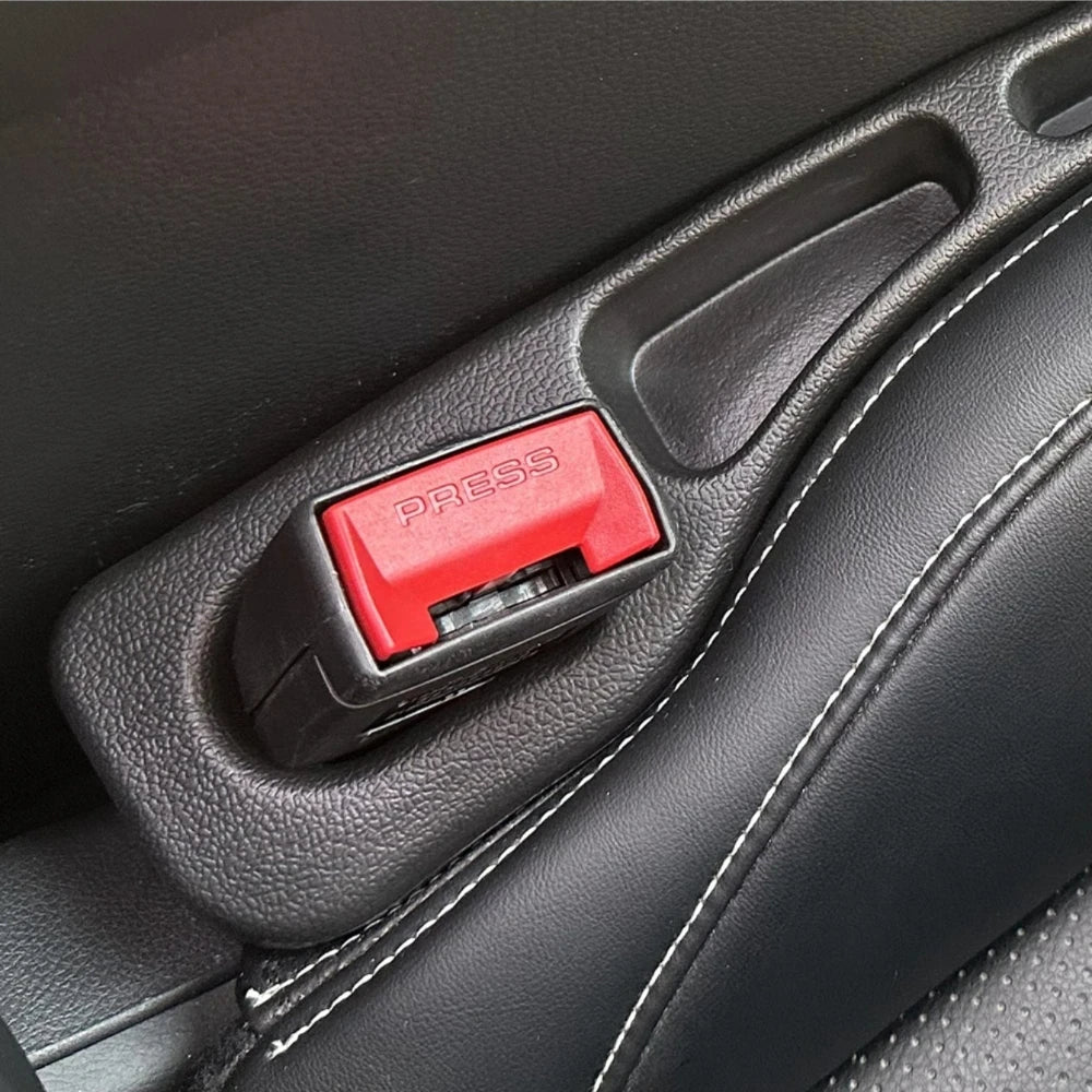 A close-up view of a black car seat gap filler organizer with a red press button.