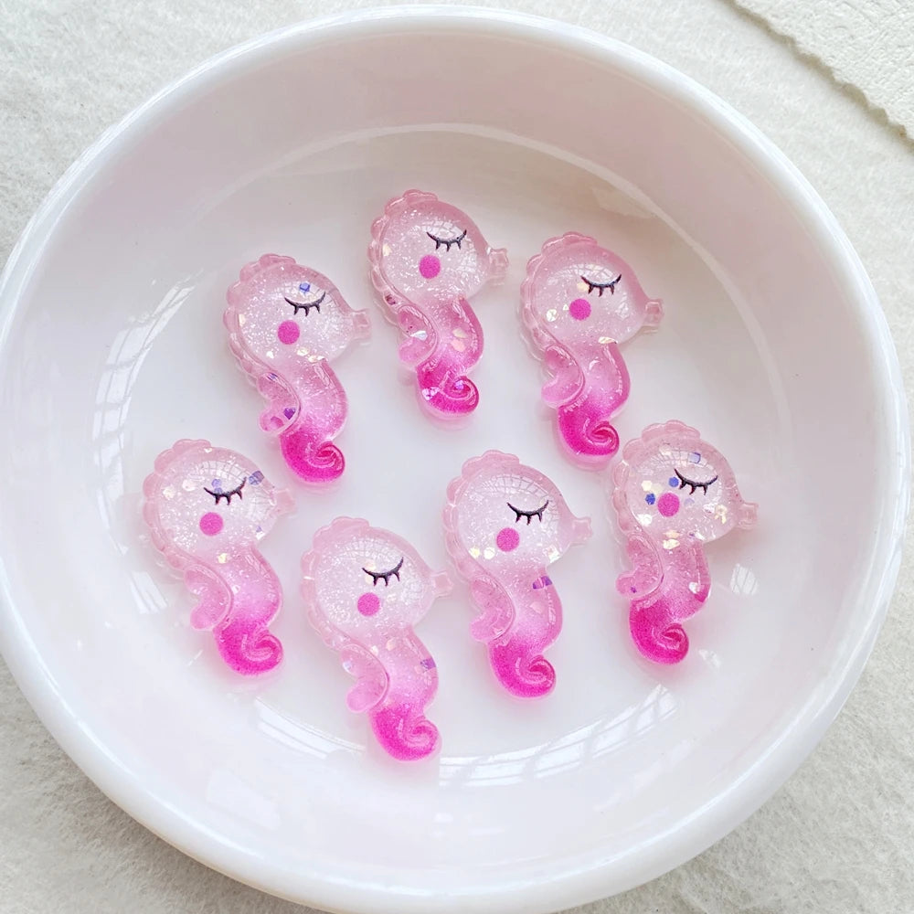 Pink and purple resin charms shaped like small fairies or spirits in a white bowl
