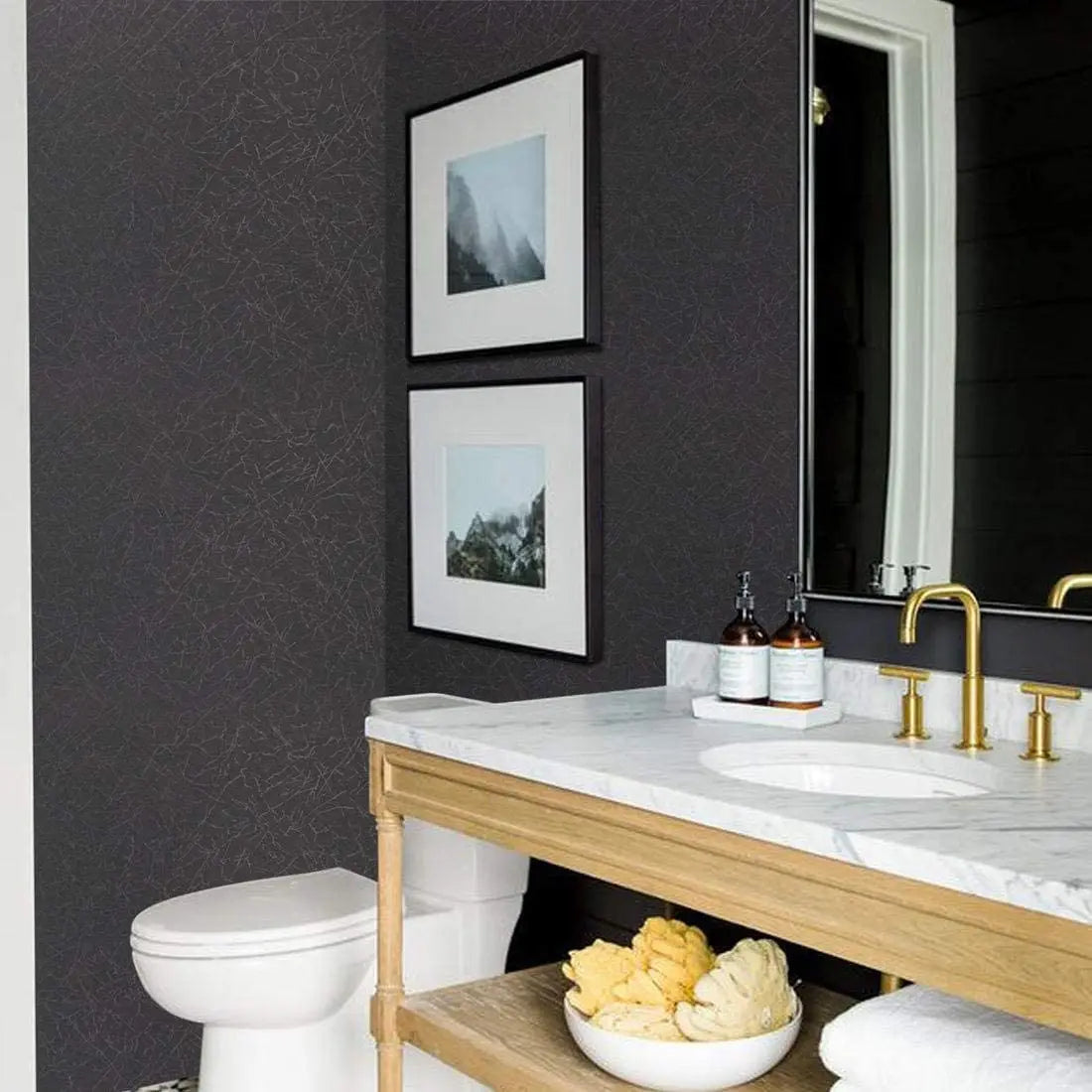 A bathroom vanity featuring a white sink and gold faucet, set against a dark gray wall with framed art.