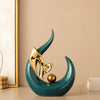 A teal ceramic sculpture shaped like a stylized leaf or horn, with a gold accent, resting on a light surface.