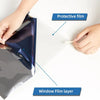 A hand is applying a protective film onto a car window, showing the window film layer and protective film.