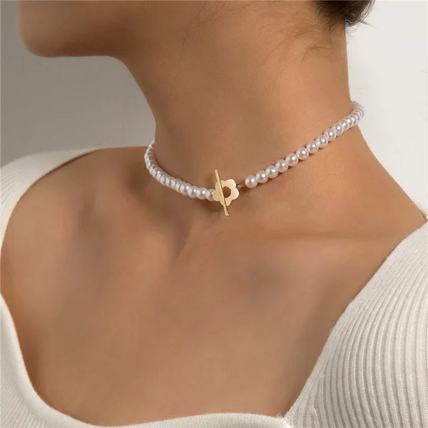 Gros plan d'un collier ras-du-cou en perles de nacre avec un pendentif de lettre en or.