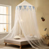 A sheer white mosquito net canopy draped over a bed, featuring light blue triangular accents.