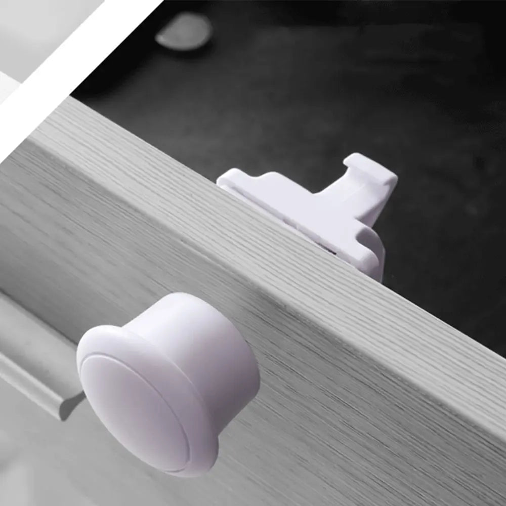 Close-up of white magnetic cabinet locks installed on a wooden cabinet door frame.