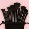 Ein Set schwarzer veganer Luxus-Make-up-Pinsel, gebündelt auf rosa Hintergrund.