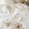 White duvet cover set with rose embroidery and lace details on a bed