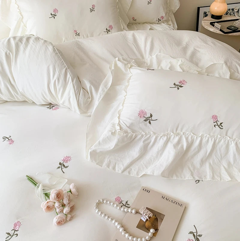 White duvet cover set with rose embroidery and lace details on a bed