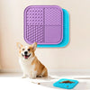 A happy dog sits next to purple and blue silicone lick mats for dogs and cats.