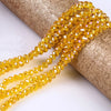 A strand of faceted yellow crystal glass spacer beads is draped over a cylindrical object.