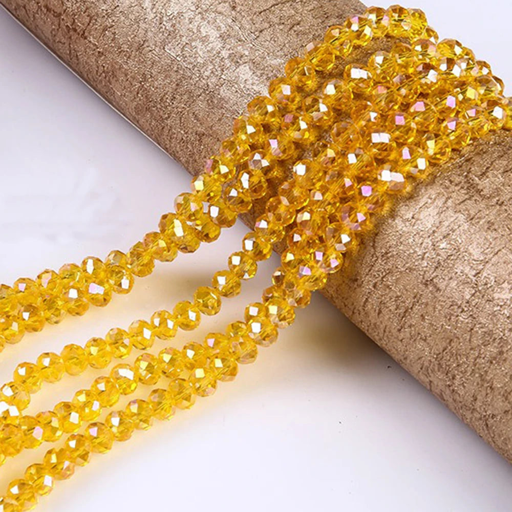 A strand of faceted yellow crystal glass spacer beads is draped over a cylindrical object.