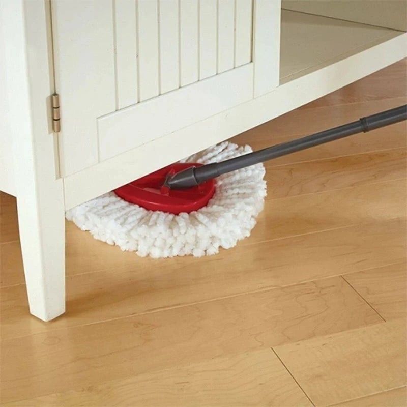 A red microfiber mop pad is resting on the floor next to a mop handle under a white cabinet.
