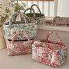 A collection of quilted fabric storage baskets in floral patterns and pinks displayed on a white shelf.