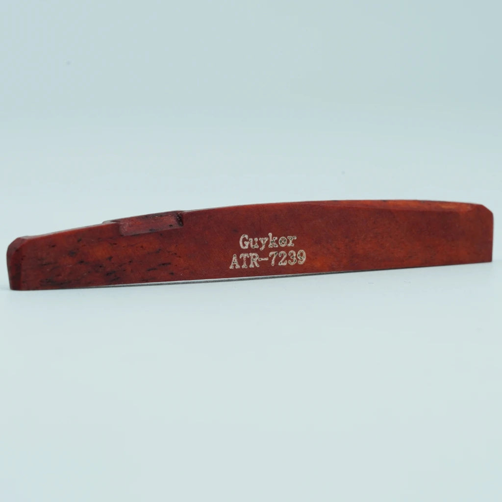 A wooden acoustic guitar bridge saddle with the inscription GUYKOAT ATR-7239