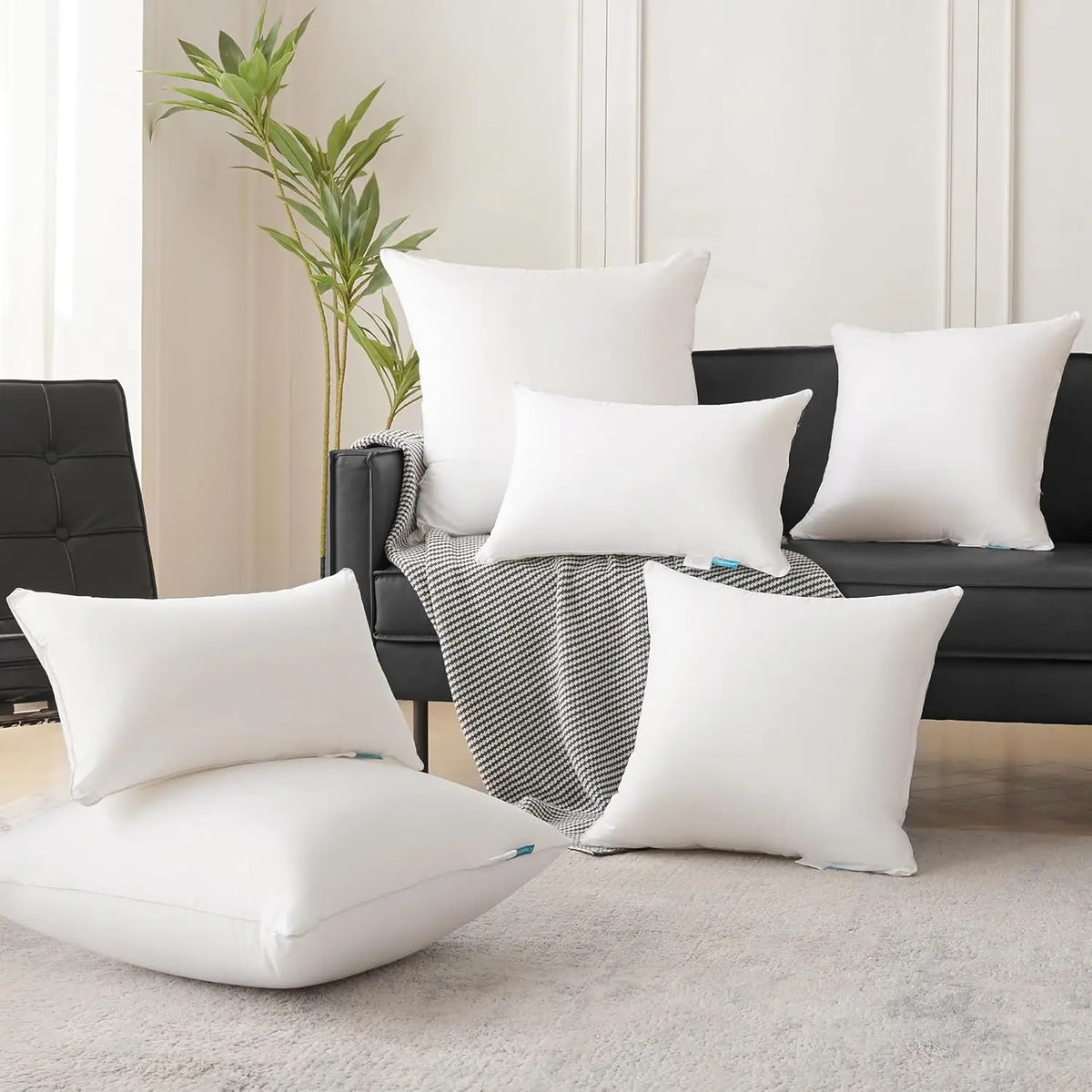 A collection of white square cushions and pillows displayed on a dark sofa with a striped throw blanket.