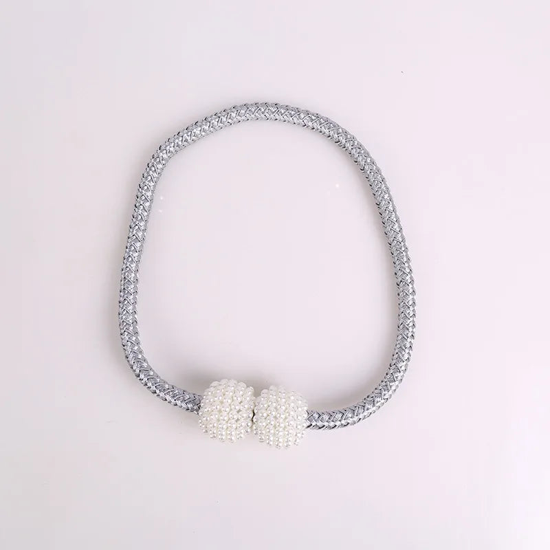 A silver-toned magnetic curtain tie-back clip featuring a pearl embellishment.