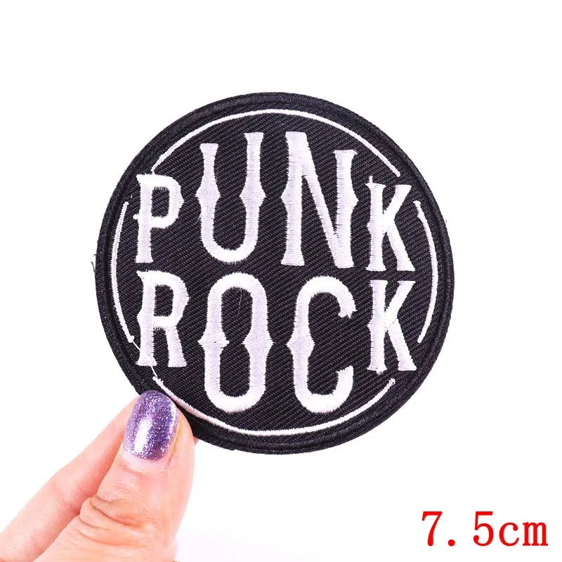 Black embroidered patch with white text PUNK ROCK on a finger