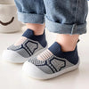 A pair of navy blue and beige breathable soft-sole baby shoes with non-slip grip shown on a person's foot.