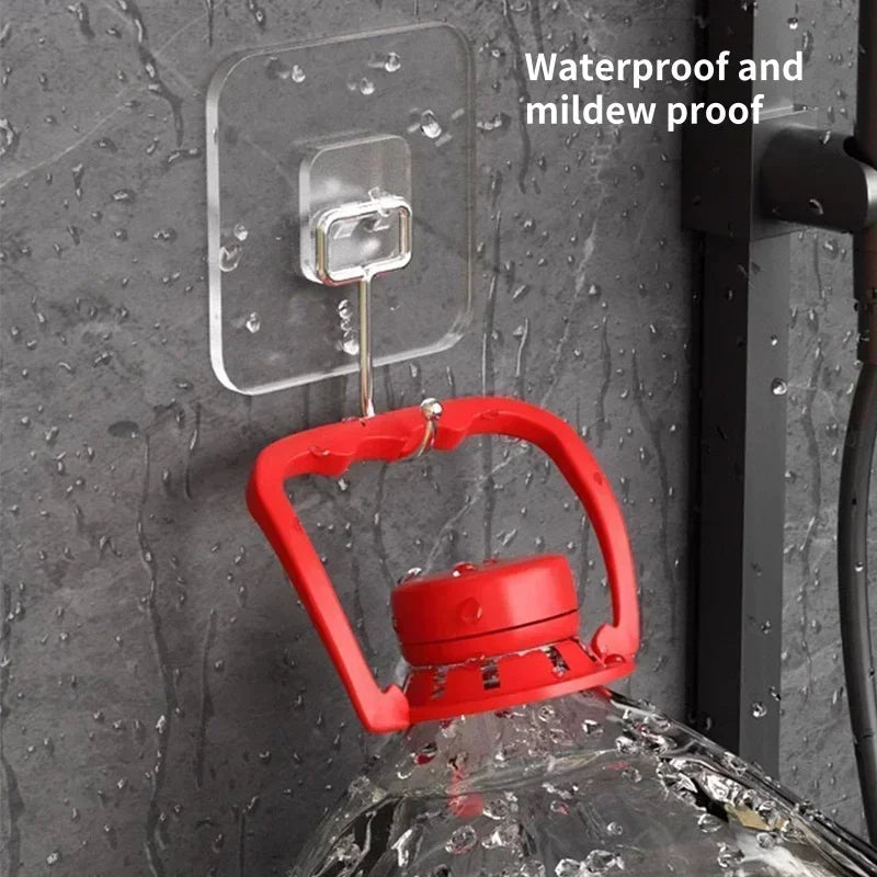 Red rotating wall hooks with a clear adhesive plate mounted on a dark gray textured wall.