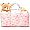 Pink floral diaper organizer bag featuring a teddy bear charm and multiple compartments for diapers and supplies