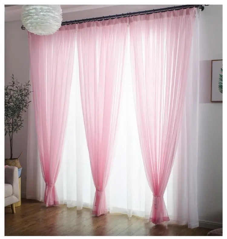 Three sheer pink voile curtains with rod pockets hanging in a bright room.