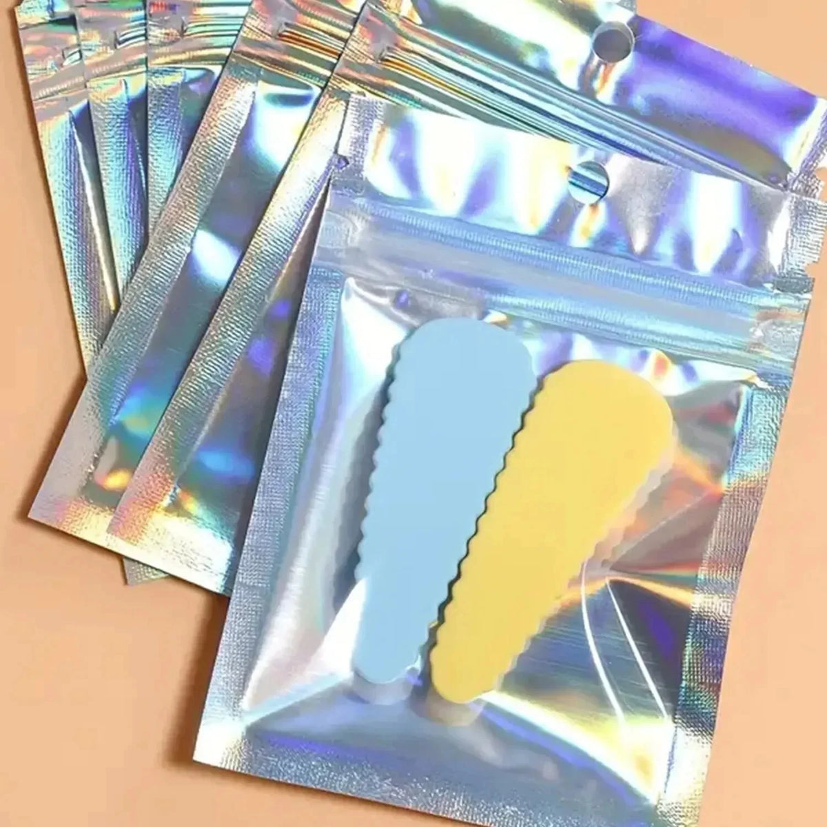 A pack of holographic rainbow self-sealing bags with clear windows containing blue and yellow items.