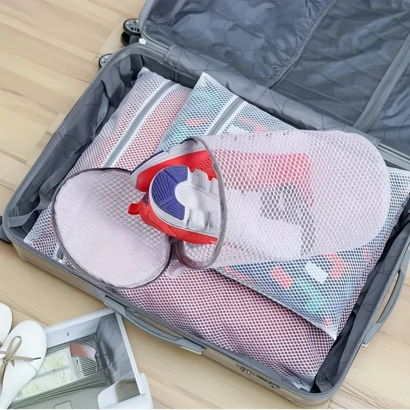 A gray storage box contains several reusable mesh laundry bags for shoes and delicates.