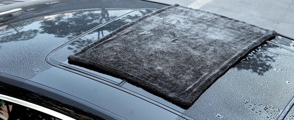 Ein dunkelgraues Mikrofasertuch wird auf die Motorhaube eines Autos gelegt.