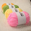 A collection of bright colored acrylic yarn skeins, including green, yellow, and pink, displayed on a white surface.