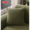A close-up of a textured olive green velvet cushion and sofa cover with quilted stitching.