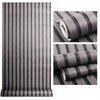 Rolls of wood grain self-adhesive wallpaper in gray tones showing vertical stripes and texture.