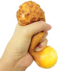 Eine Hand presst ein realistisches Spielzeug in Form eines frittierten Hähnchenschenkels.