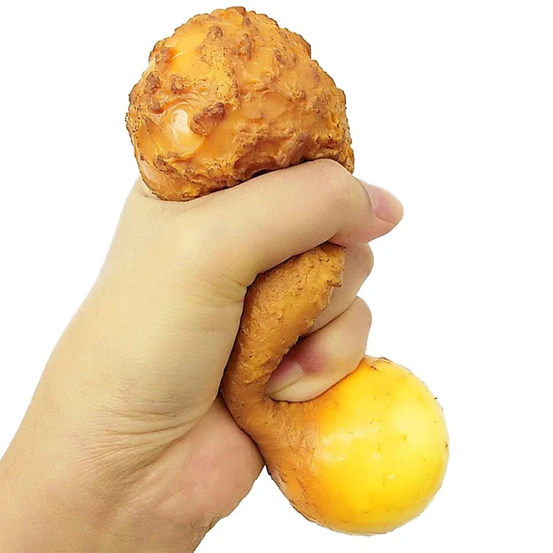 Eine Hand presst ein realistisches Spielzeug in Form eines frittierten Hähnchenschenkels.