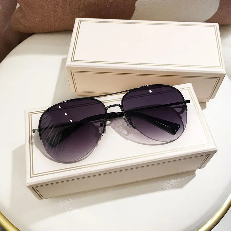 Ein Paar klassische Aviator-Sonnenbrillen mit dunklen Linsen auf einer weißen Geschenkbox.