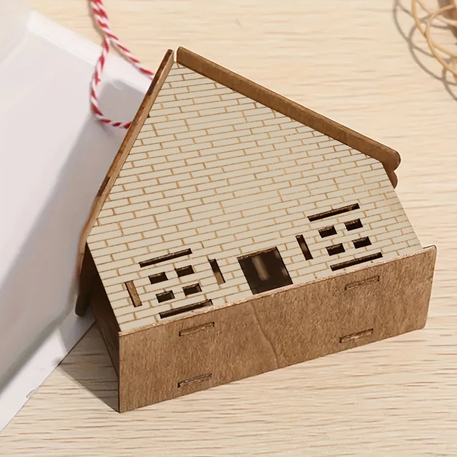 A cardboard model of a house built with a brick pattern stencil, shown on a wooden surface.
