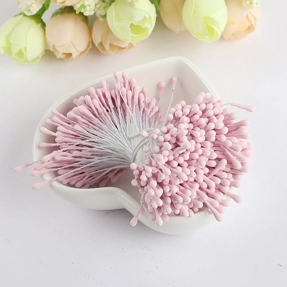 A pile of pink pearl flower stamens for DIY crafts and wedding decor, alongside light green and peach flowers.